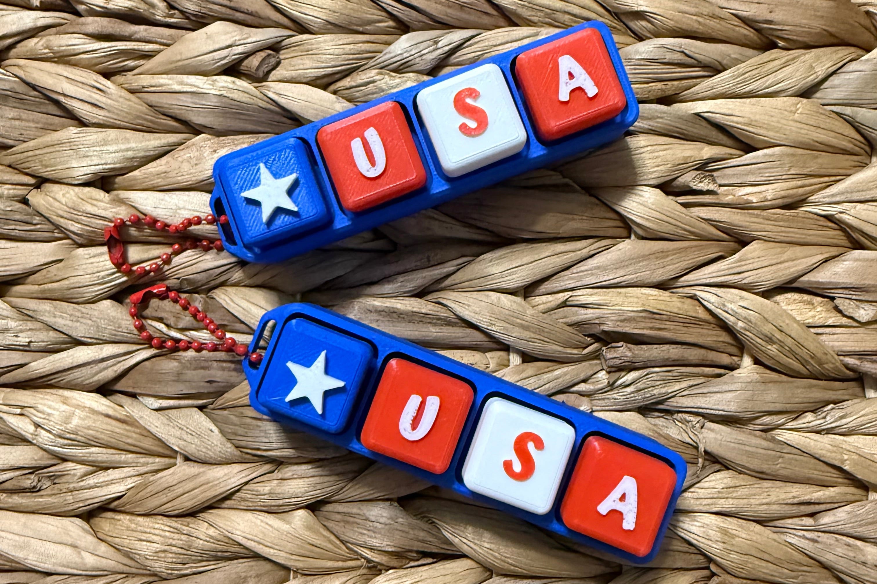 Two keychains with 'USA' and star design on a woven surface