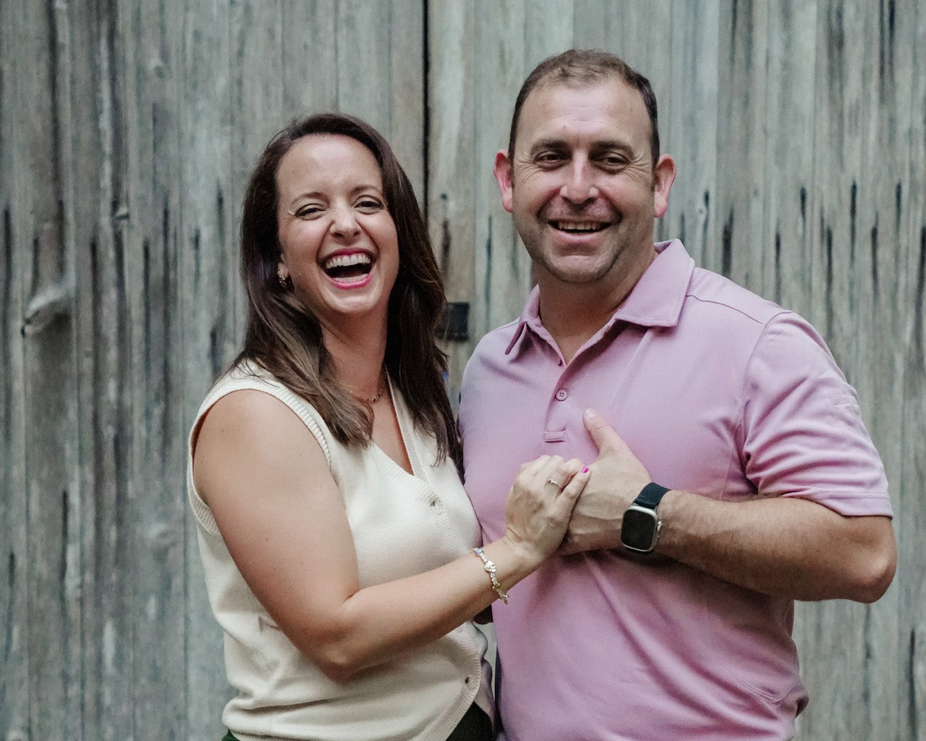 Man and woman standing together in front of a wooden wall