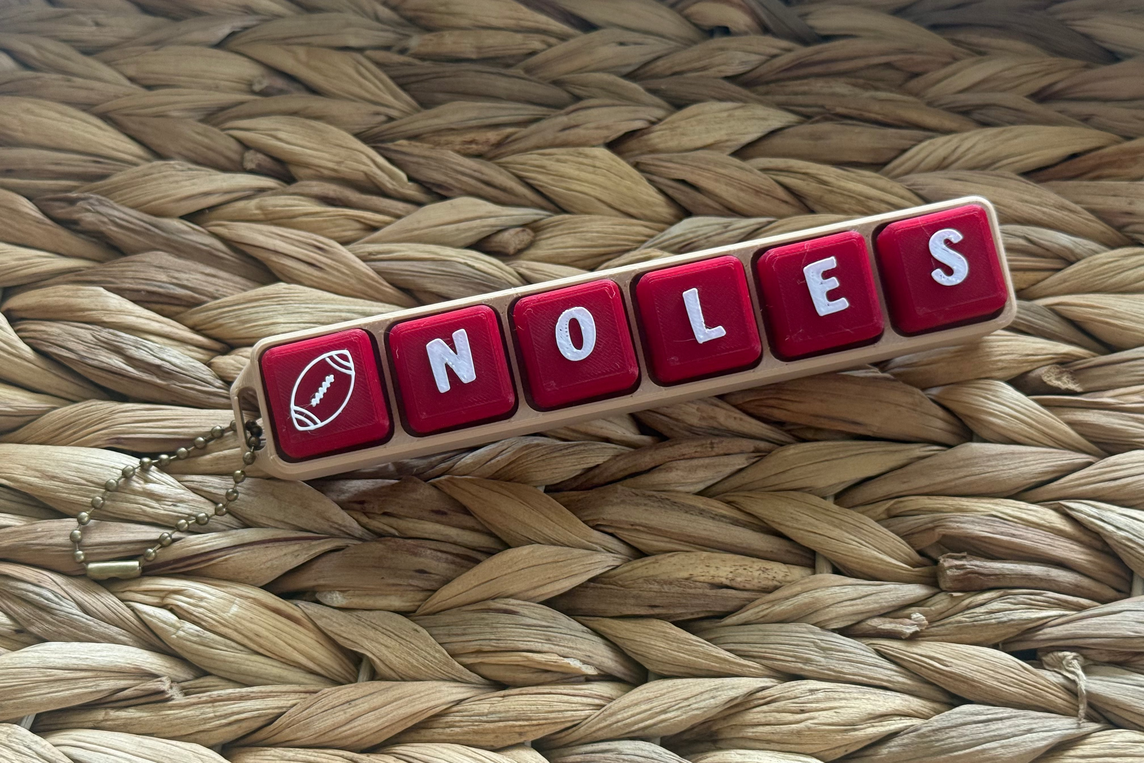 Red and white 'Noles' keychain on a woven surface