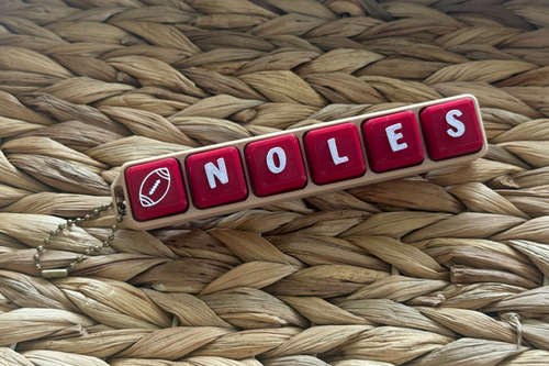 Red and white 'Noles' keychain on a woven surface