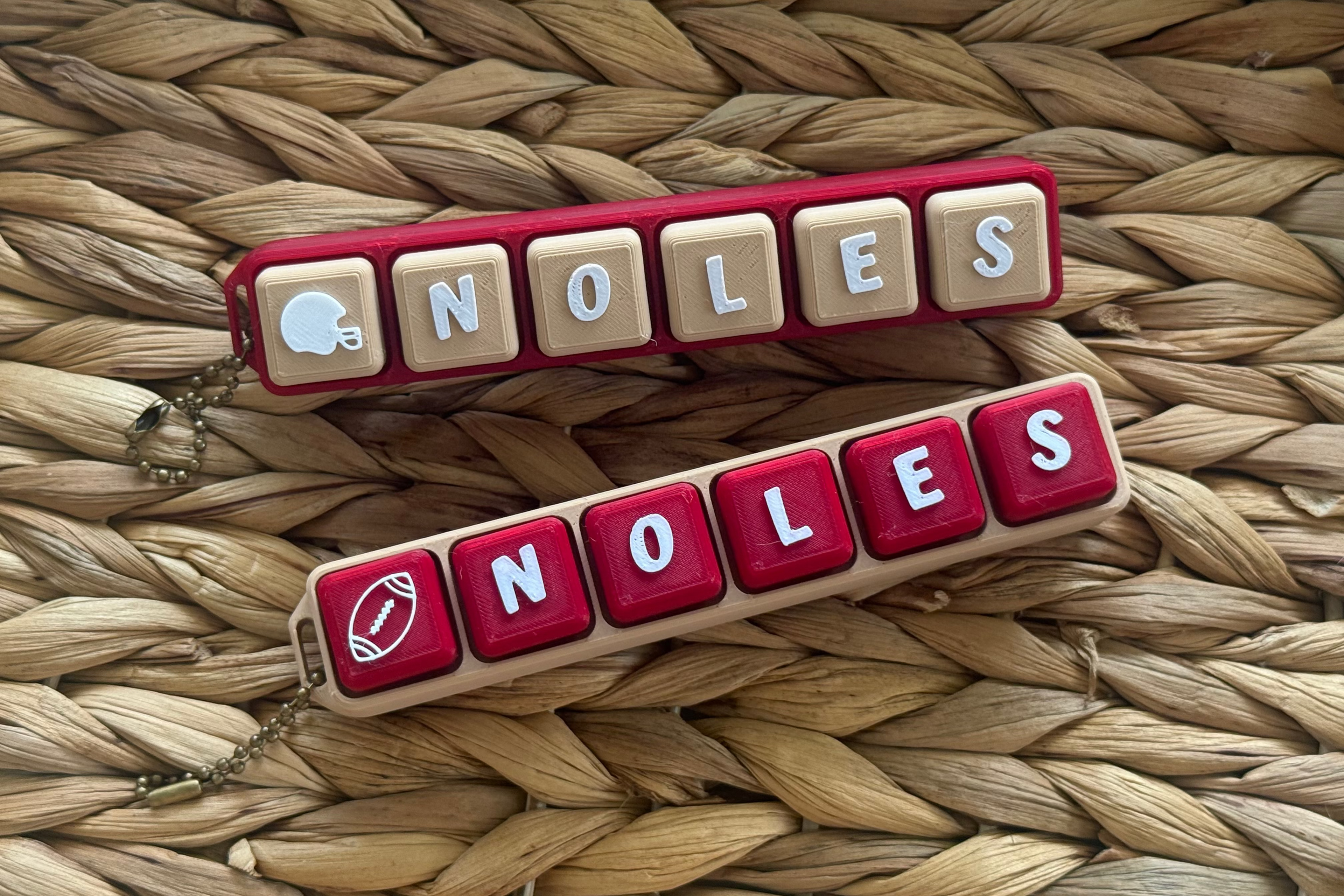 Two 'NOLAS' keychains on a woven surface