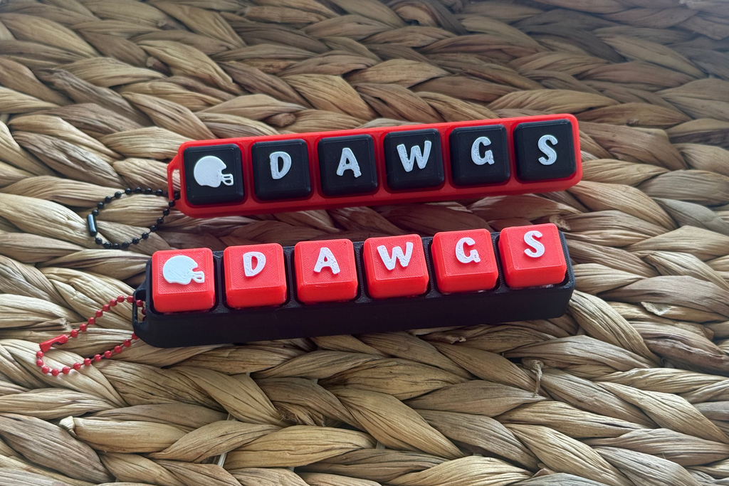 Two keychain designs with 'DAWGS' text on a woven surface