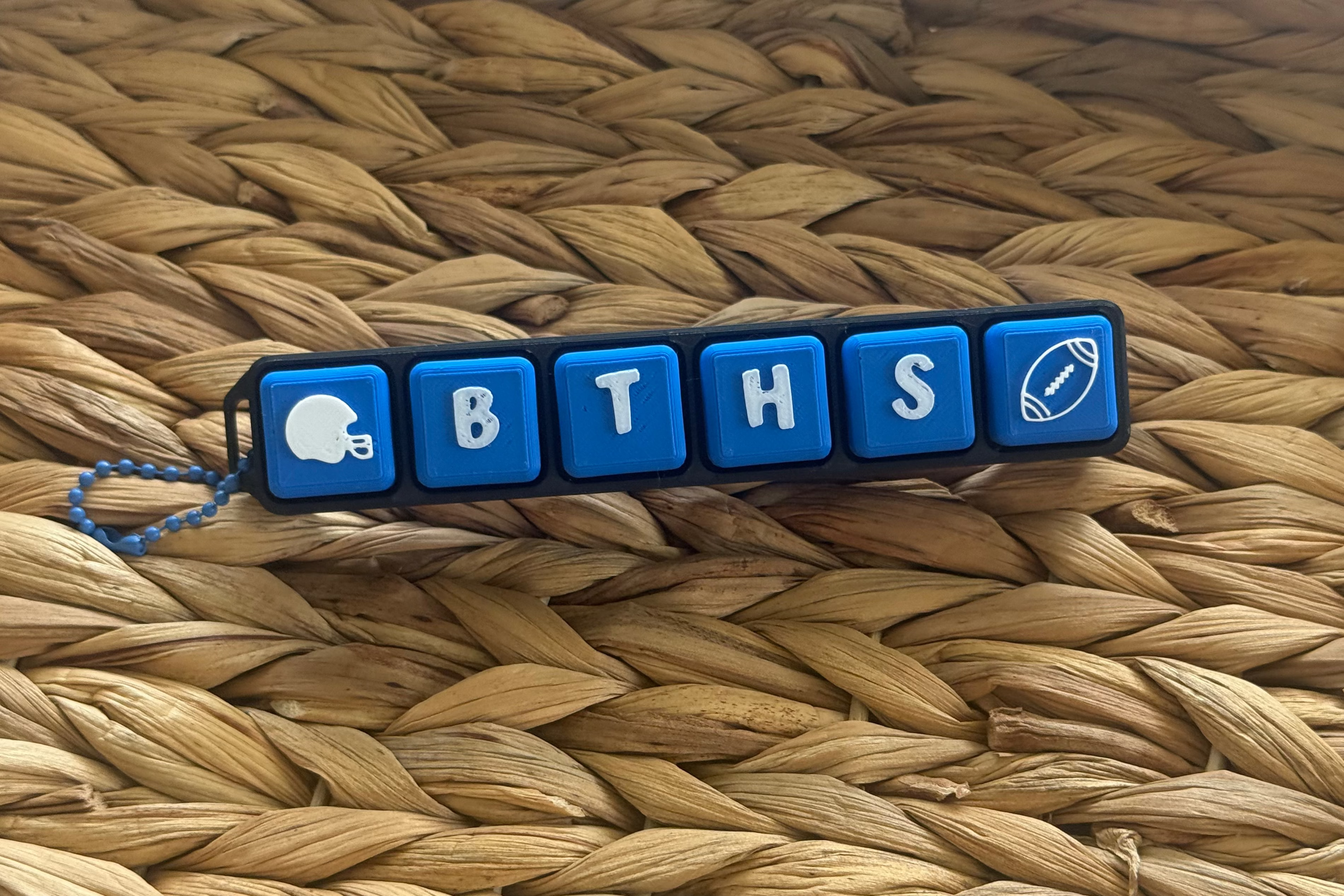 Blue keychain with letter blocks spelling 'BTHS' on a woven surface