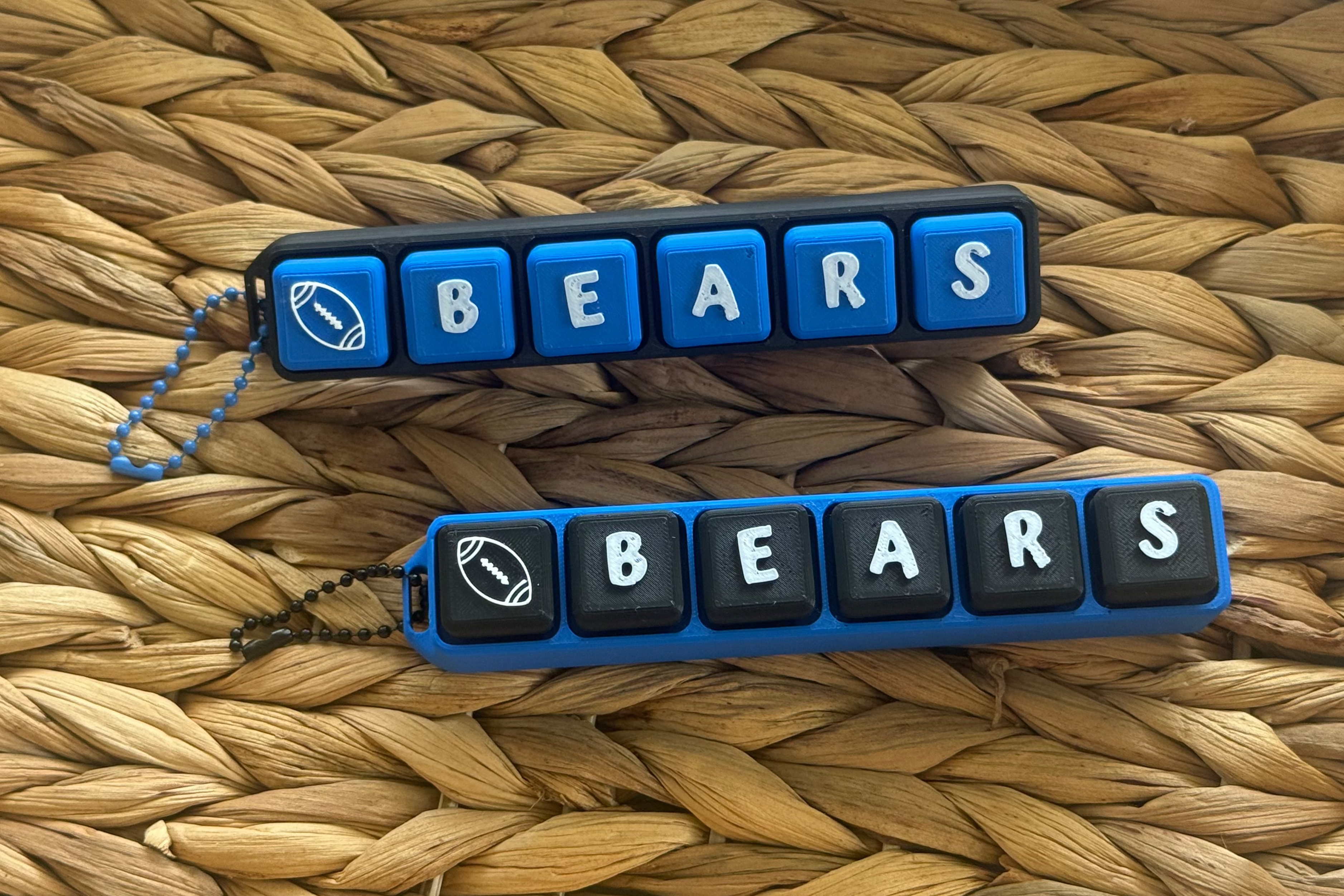 Two keychains with 'BEARS' text on a woven surface